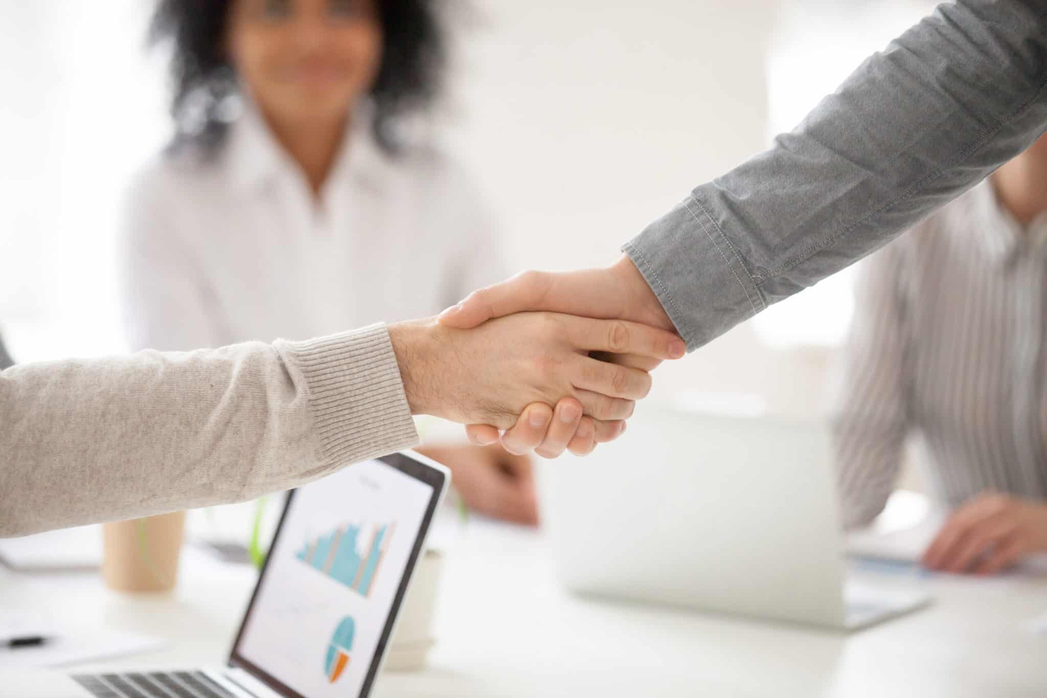 Two business partners handshake at group meeting making online project investment, male hands shake as concept of successful collaboration result or starting partnership after effective negotiations